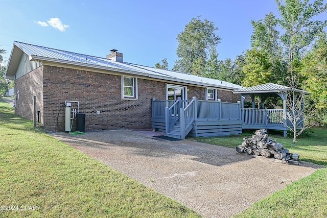 back of property with metal roof, brick siding, a yard, and a chimney