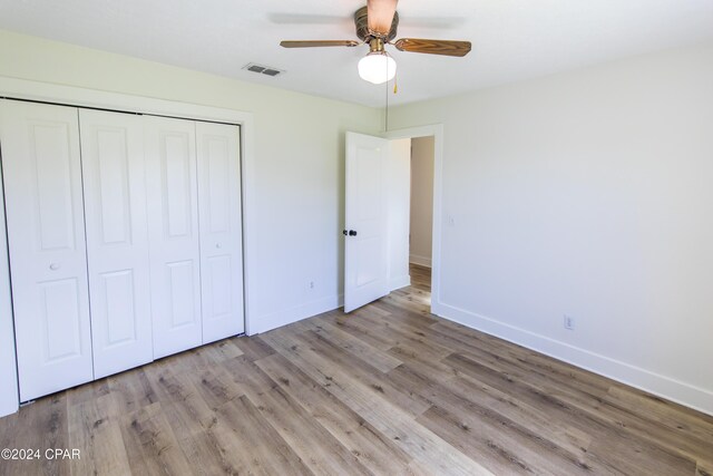 unfurnished bedroom featuring light hardwood / wood-style flooring, a closet, and ceiling fan