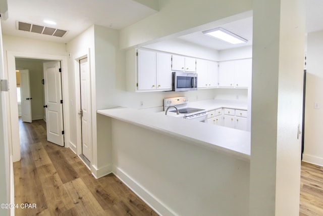 kitchen featuring white cabinets, light wood-type flooring, electric range, and kitchen peninsula