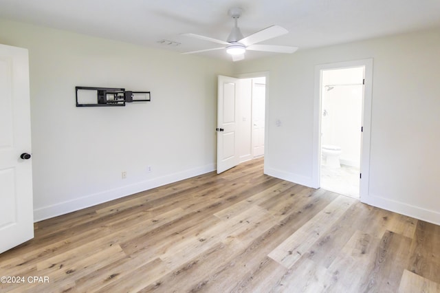 unfurnished bedroom with ensuite bath, ceiling fan, and light wood-type flooring