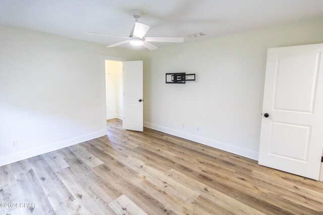 empty room with ceiling fan and light hardwood / wood-style flooring