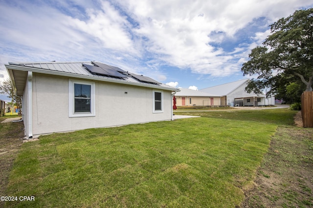 back of property with a yard and solar panels