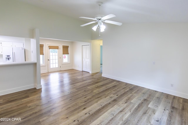 unfurnished living room with ceiling fan, vaulted ceiling, and light wood-type flooring