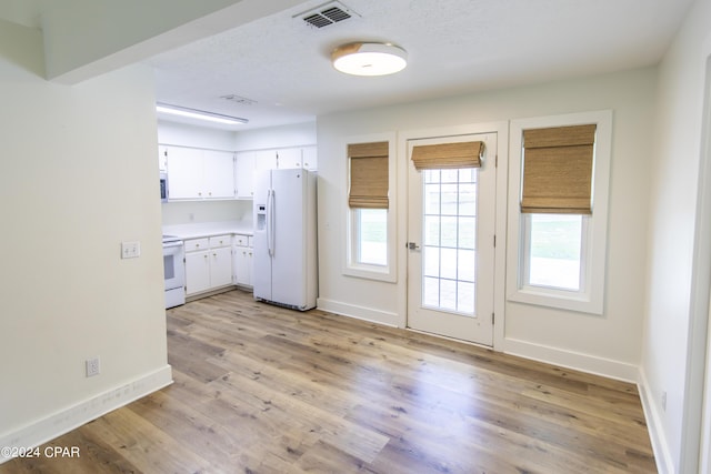 kitchen with a textured ceiling, light hardwood / wood-style flooring, white cabinets, and white appliances