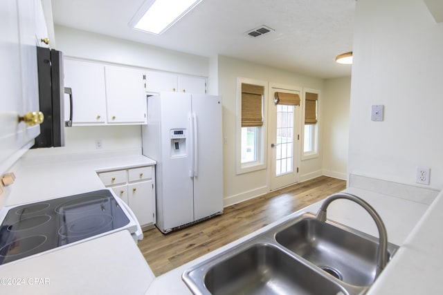 kitchen with light hardwood / wood-style floors, white appliances, white cabinetry, and sink