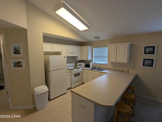 kitchen with lofted ceiling, white cabinetry, white appliances, and kitchen peninsula