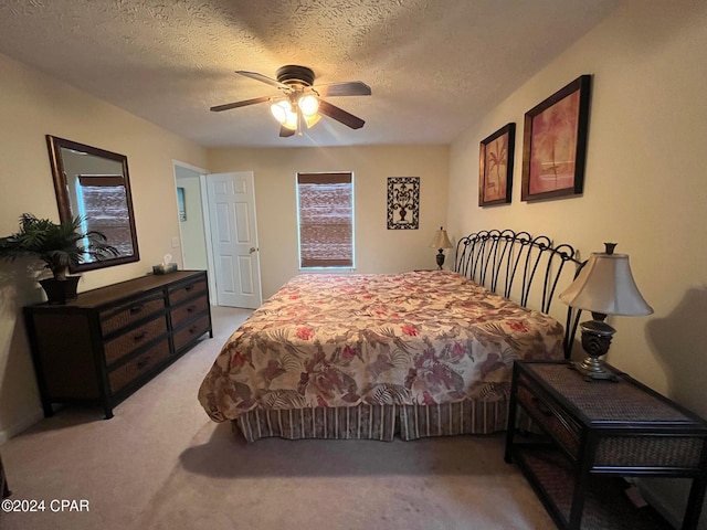 bedroom with ceiling fan, a textured ceiling, and light carpet