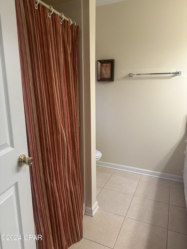 bathroom with a shower with curtain, tile patterned flooring, and toilet