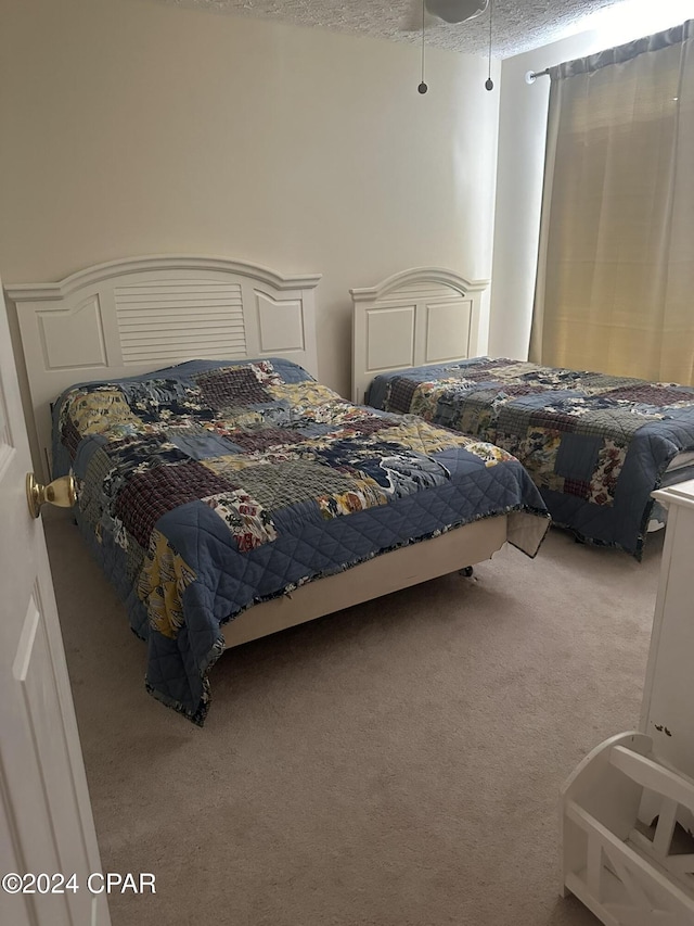 carpeted bedroom featuring ceiling fan and a textured ceiling