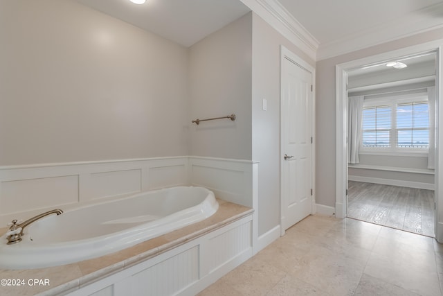 bathroom with ornamental molding, a tub to relax in, and hardwood / wood-style floors