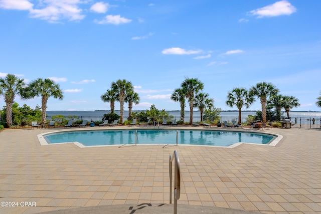 view of swimming pool featuring a patio area and a water view