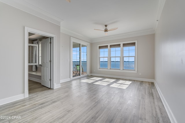 spare room with crown molding, a water view, and light hardwood / wood-style floors