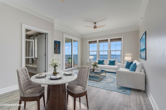 dining room featuring a water view, ceiling fan, wood-type flooring, and ornamental molding