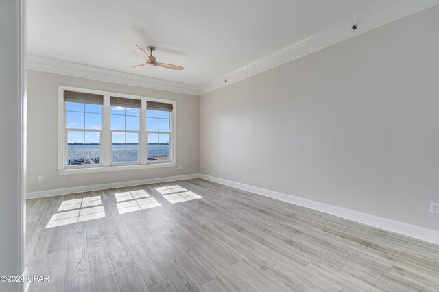 spare room featuring light hardwood / wood-style floors, ornamental molding, a water view, and ceiling fan