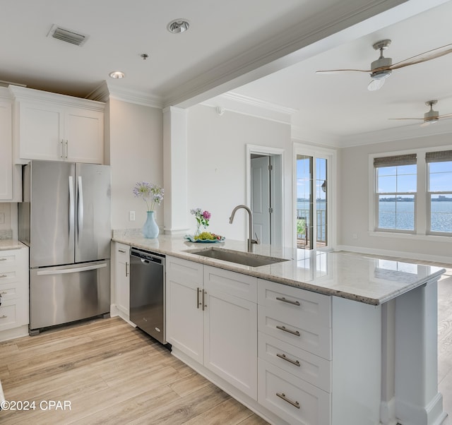 kitchen with white cabinets, light hardwood / wood-style flooring, sink, crown molding, and stainless steel appliances