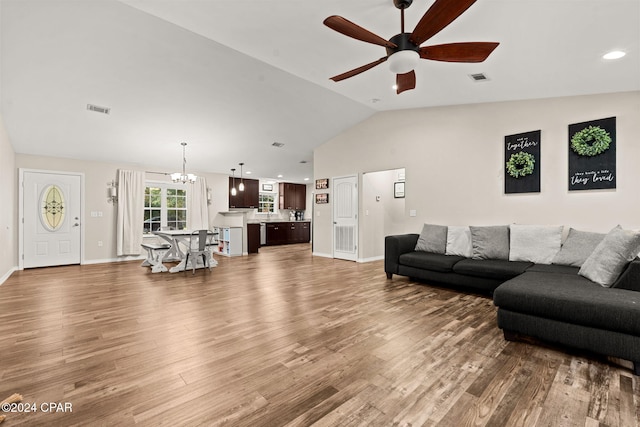 living room featuring hardwood / wood-style flooring, lofted ceiling, and ceiling fan with notable chandelier