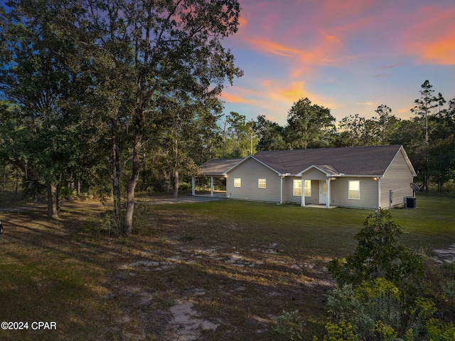 view of front of home with central air condition unit and a yard