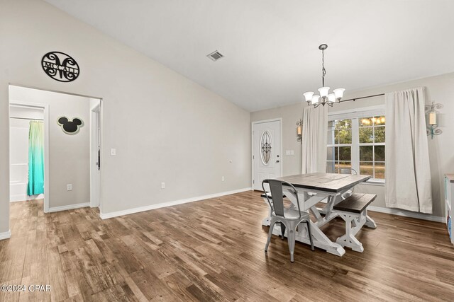 dining space featuring wood-type flooring, lofted ceiling, and an inviting chandelier