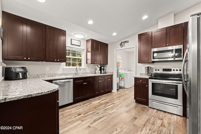 kitchen featuring lofted ceiling, light stone countertops, separate washer and dryer, light wood-type flooring, and appliances with stainless steel finishes