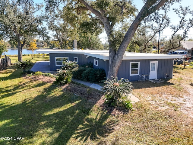 back of property with a lawn and a water view