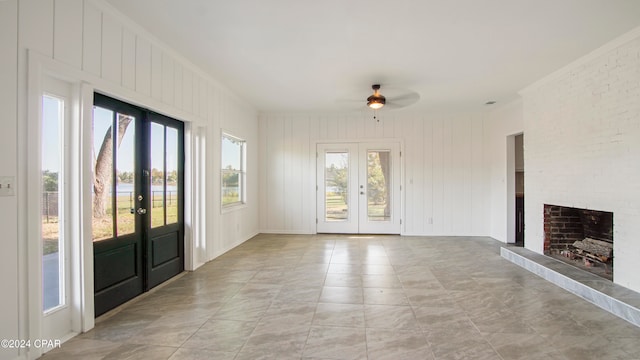 interior space with a brick fireplace, ceiling fan, and french doors