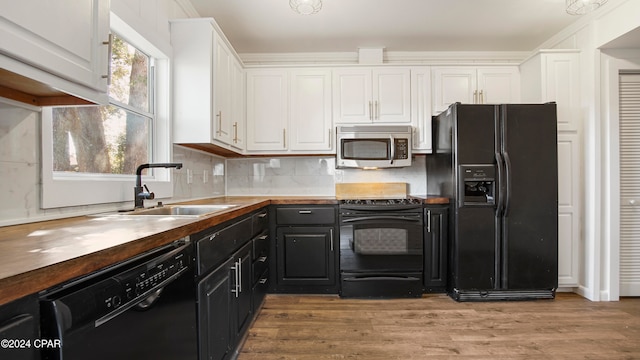 kitchen featuring white cabinetry, sink, butcher block countertops, black appliances, and light wood-type flooring