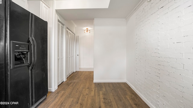 hall featuring a skylight, dark hardwood / wood-style flooring, and brick wall