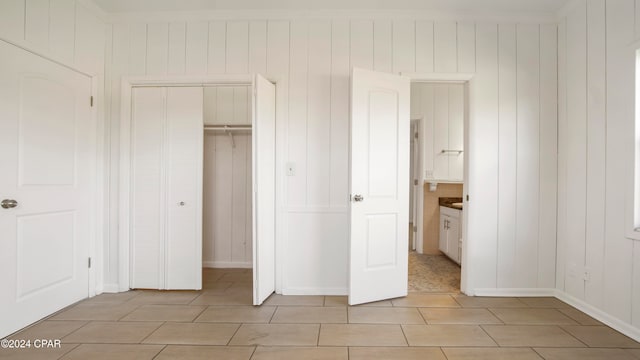 unfurnished bedroom with a closet and wood walls