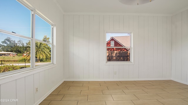 unfurnished room featuring wooden walls, ceiling fan, and ornamental molding