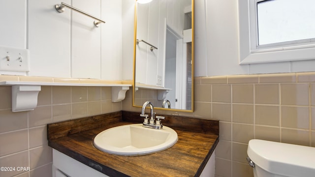 bathroom featuring vanity, toilet, backsplash, and tile walls