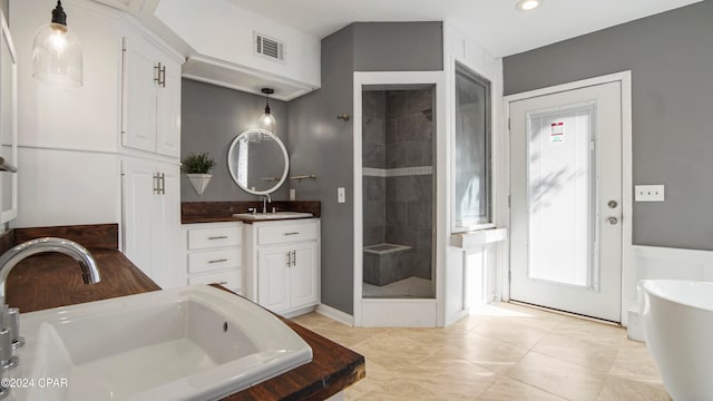 bathroom featuring shower with separate bathtub, vanity, and tile patterned floors