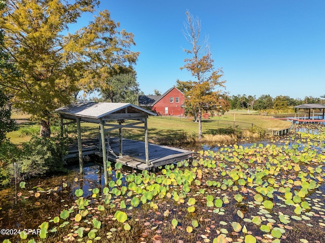 view of dock with a rural view and a lawn