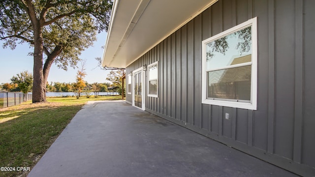 view of side of property with a lawn, a patio area, and a water view