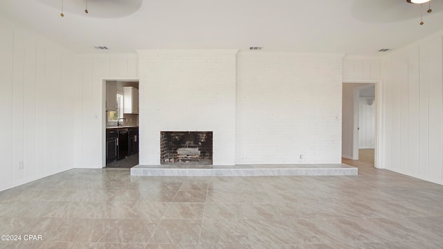 unfurnished living room with a fireplace, sink, ceiling fan, and wood walls