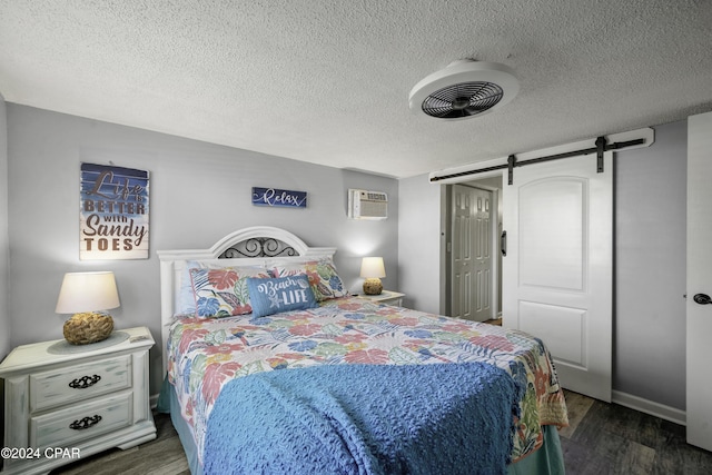 202 3rd St, Mexico Beach, FL 32456 - bedroom with wood finished floors, a barn door, a textured ceiling, a wall unit AC, and a closet