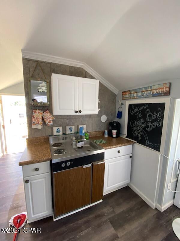 kitchen featuring dark hardwood / wood-style flooring, white cabinetry, and vaulted ceiling