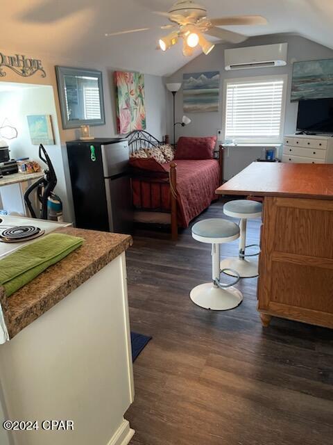 202 3rd St, Mexico Beach, FL 32456 - bedroom featuring a wall mounted air conditioner, freestanding refrigerator, dark wood-style flooring, vaulted ceiling, and ceiling fan