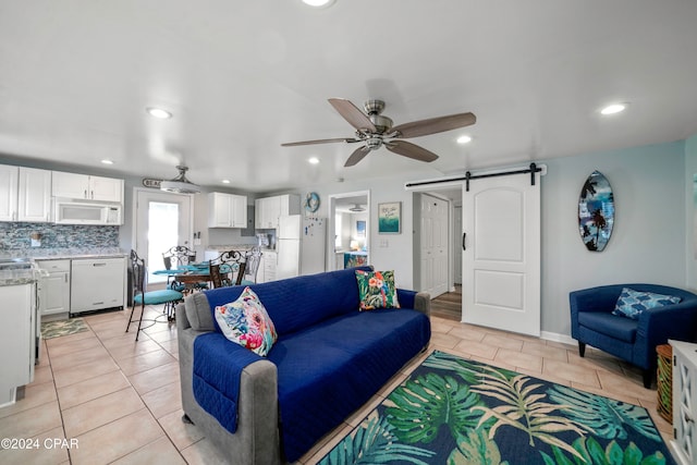 tiled living room with a barn door and ceiling fan