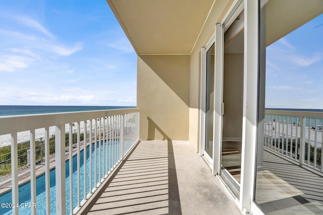 balcony with a water view and a view of the beach