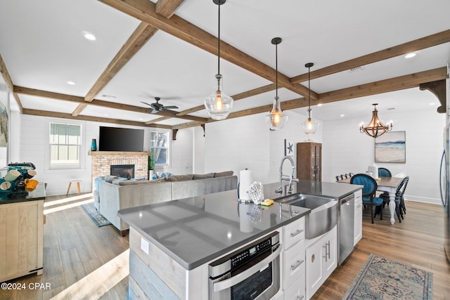 kitchen with a large island, sink, white cabinetry, and hanging light fixtures