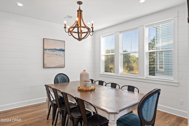 dining room featuring wooden walls, dark wood-type flooring, and a notable chandelier