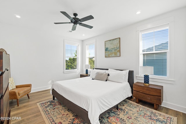 bedroom with multiple windows, ceiling fan, and hardwood / wood-style floors