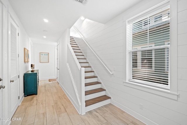 staircase featuring hardwood / wood-style flooring and wooden walls