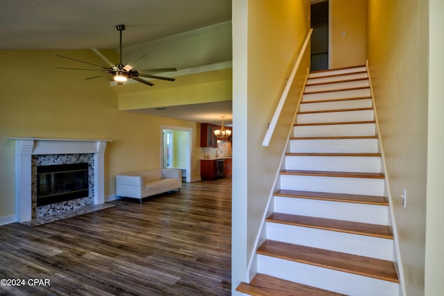 staircase featuring hardwood / wood-style floors, ceiling fan, ornamental molding, a tile fireplace, and sink