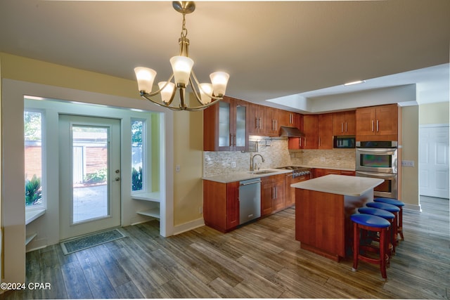 kitchen with appliances with stainless steel finishes, a center island, decorative light fixtures, dark wood-type flooring, and ventilation hood