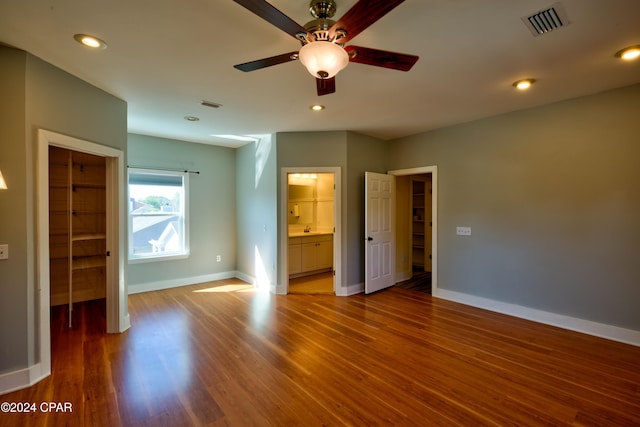 unfurnished bedroom featuring connected bathroom, hardwood / wood-style floors, a closet, and ceiling fan