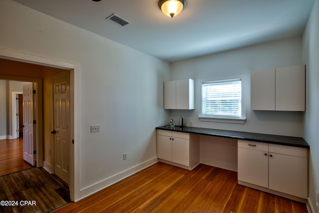 kitchen featuring white cabinets, built in desk, hardwood / wood-style floors, and sink