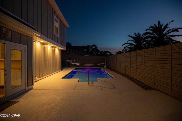 pool at dusk with a patio area