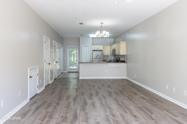 kitchen featuring cream cabinets, kitchen peninsula, light hardwood / wood-style floors, stainless steel appliances, and a chandelier