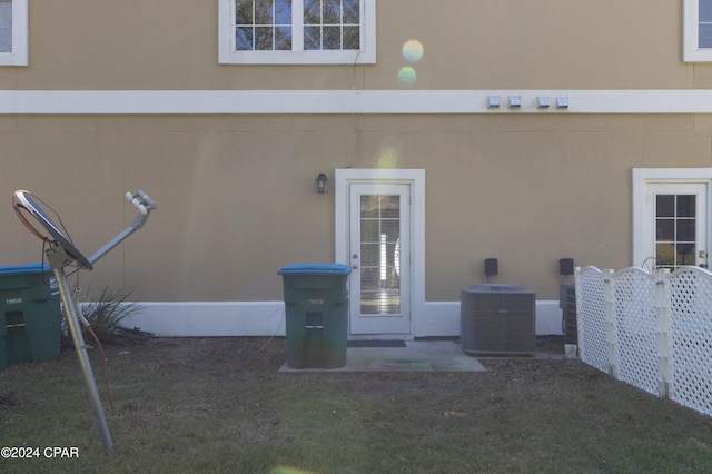 doorway to property featuring central AC and a lawn